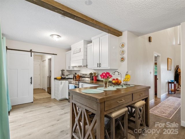 kitchen with a textured ceiling, stainless steel electric range oven, dark countertops, and light wood-style floors
