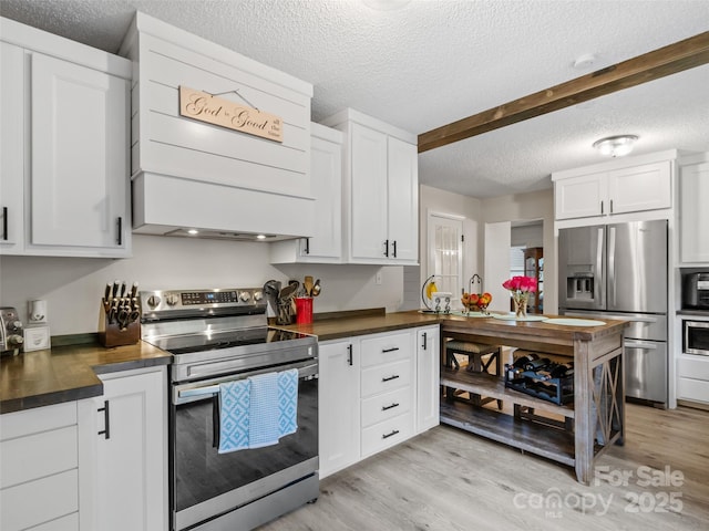 kitchen featuring light wood-style flooring, premium range hood, appliances with stainless steel finishes, and a textured ceiling