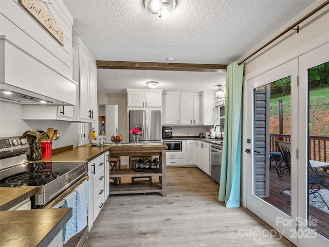 kitchen featuring a textured ceiling, a sink, dark countertops, stainless steel appliances, and white cabinets