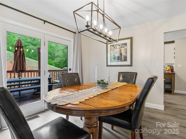 dining room featuring baseboards, an inviting chandelier, light wood-style flooring, and visible vents