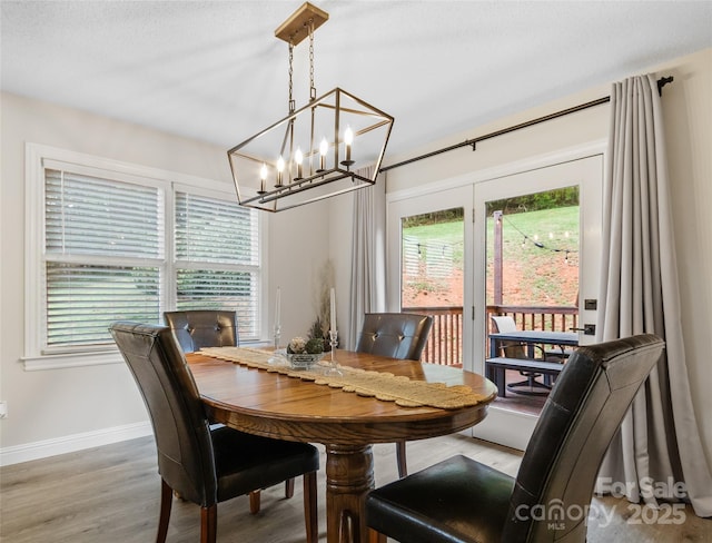 dining room with baseboards, an inviting chandelier, and wood finished floors