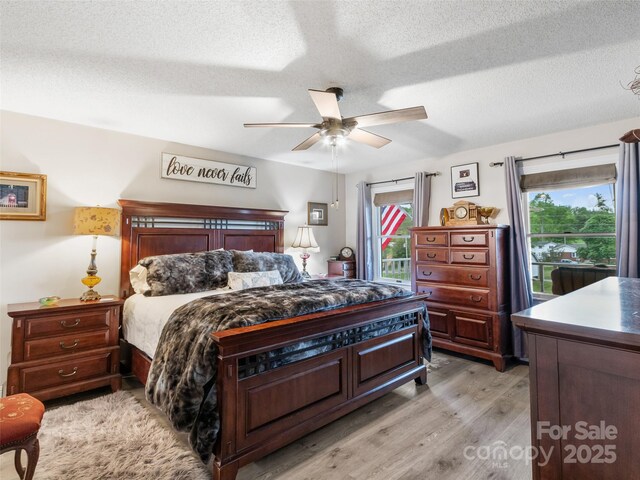 bedroom featuring a ceiling fan, light wood-type flooring, and a textured ceiling