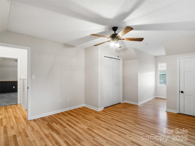 unfurnished bedroom with lofted ceiling, baseboards, and light wood-type flooring