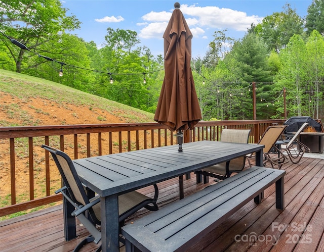 wooden deck featuring outdoor dining area and a forest view