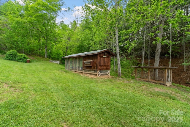 view of yard featuring an outbuilding, a wooded view, and exterior structure