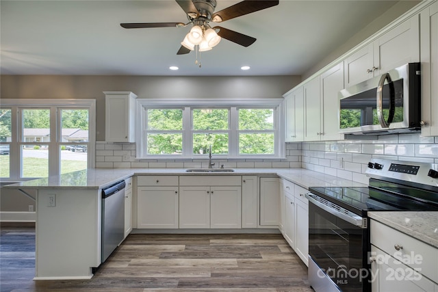 417 Mountain View Ave SE, Valdese, NC 28690 - kitchen with appliances with stainless steel finishes, a sink, a peninsula, light wood finished floors, and white cabinets