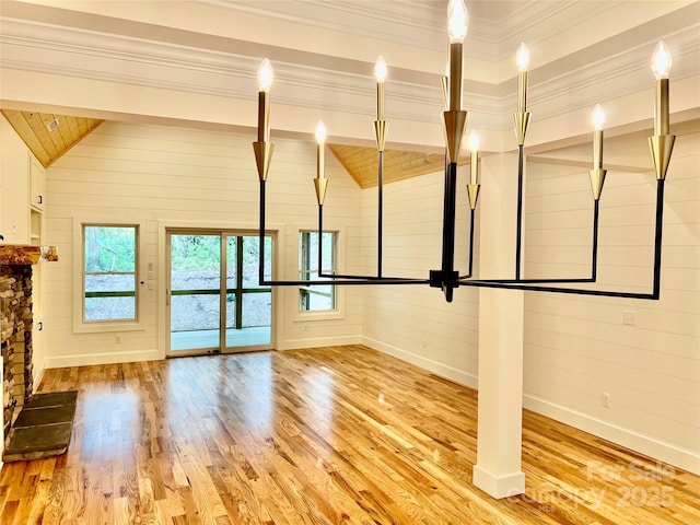 unfurnished living room with wood finished floors, baseboards, plenty of natural light, and wood walls