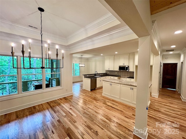 kitchen featuring stainless steel microwave, crown molding, white cabinets, light wood-style floors, and baseboards