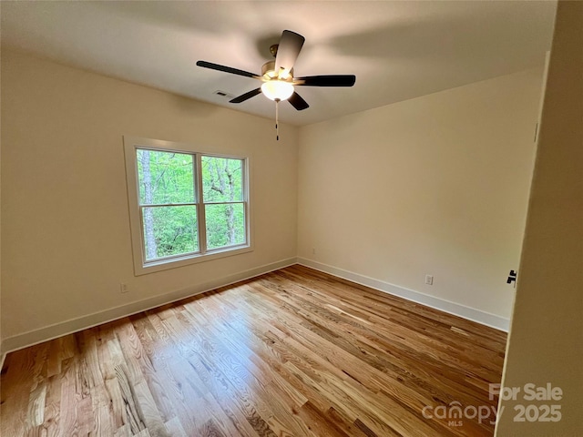 unfurnished room featuring wood finished floors, baseboards, and a ceiling fan
