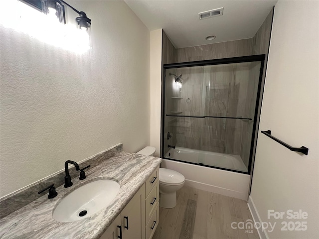 full bath featuring wood finished floors, toilet, shower / bath combination with glass door, and vanity