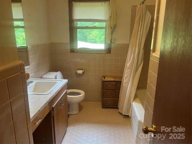 full bathroom with toilet, wainscoting, tile walls, vanity, and shower / tub combo