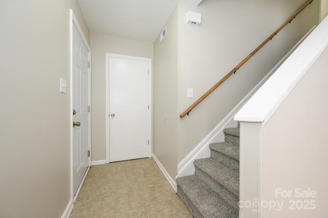 foyer entrance with stairs and baseboards