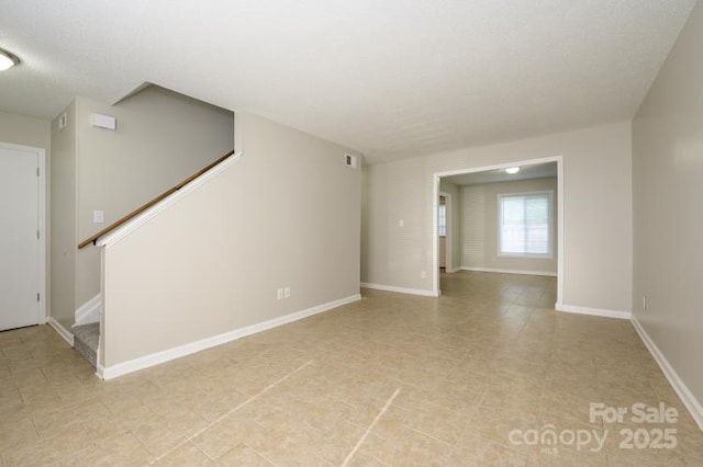 empty room featuring stairway and baseboards