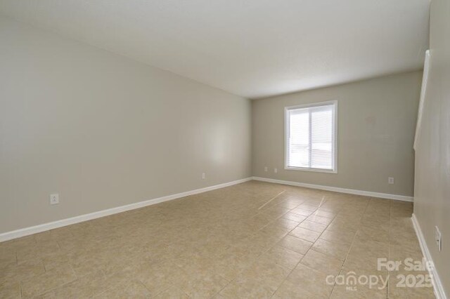 unfurnished room with baseboards and light tile patterned floors