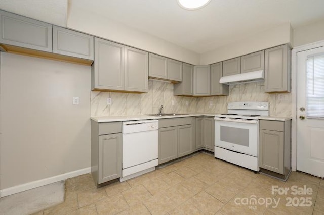 kitchen featuring gray cabinets, white appliances, under cabinet range hood, a sink, and backsplash