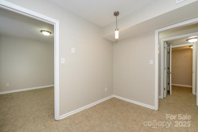 empty room featuring baseboards and light tile patterned flooring