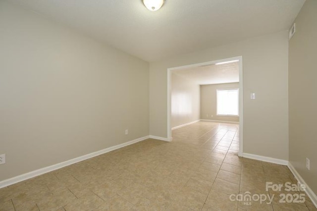 empty room featuring baseboards and light tile patterned floors