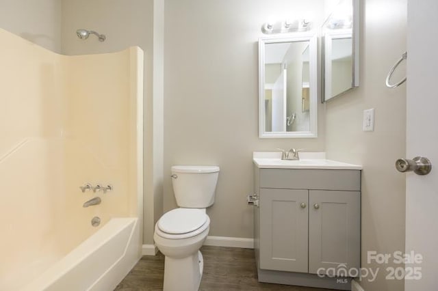 full bath featuring toilet, wood finished floors, baseboards, vanity, and  shower combination