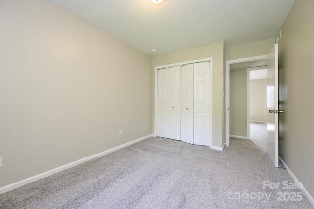 unfurnished bedroom with carpet, a closet, and baseboards