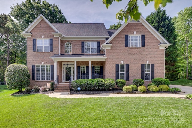 colonial house featuring a front yard, brick siding, and covered porch