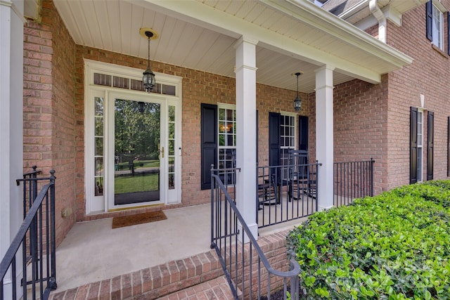 property entrance featuring covered porch and brick siding