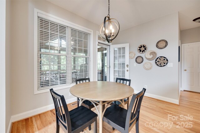 dining room with a chandelier, light wood-type flooring, and baseboards
