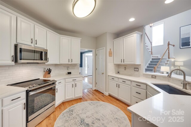 kitchen with stainless steel appliances, a sink, healthy amount of natural light, white cabinets, and recessed lighting