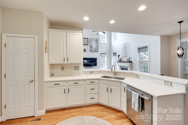 kitchen featuring a fireplace, a sink, dishwasher, ceiling fan, and tasteful backsplash