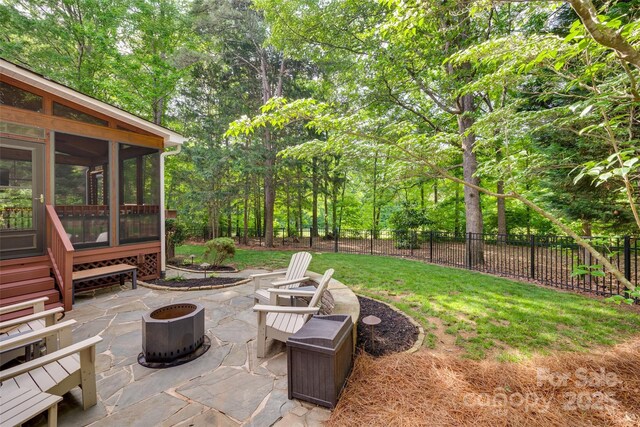 view of yard featuring a fire pit, a patio area, and a sunroom