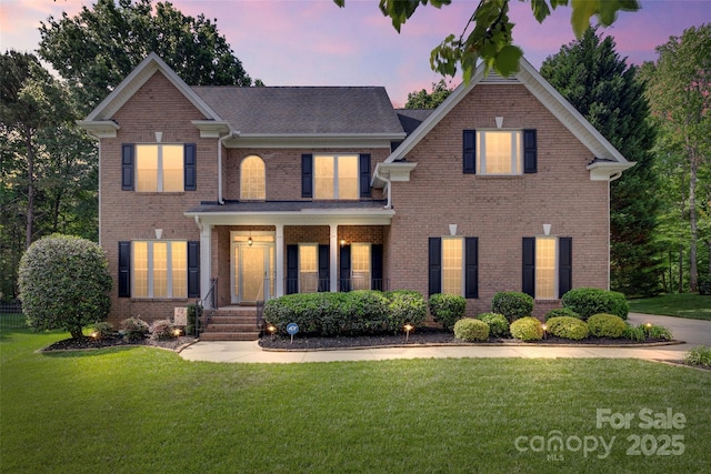 colonial-style house featuring a front lawn, brick siding, and covered porch