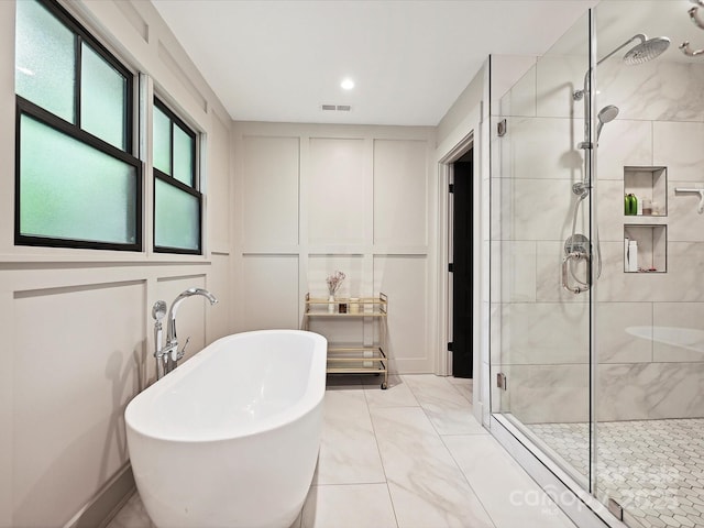 bathroom featuring a decorative wall, a stall shower, a freestanding tub, marble finish floors, and recessed lighting