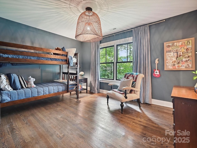 bedroom featuring baseboards, wood finished floors, and a chandelier