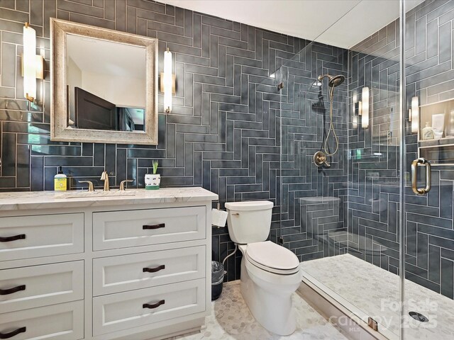 bathroom with a shower stall, toilet, vanity, tile walls, and backsplash