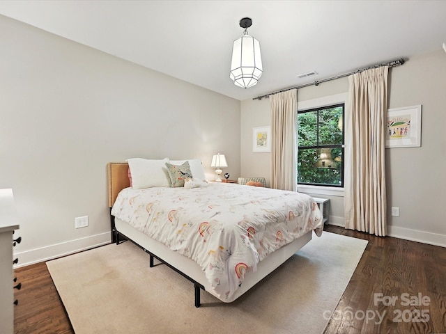 bedroom with dark wood-type flooring and baseboards