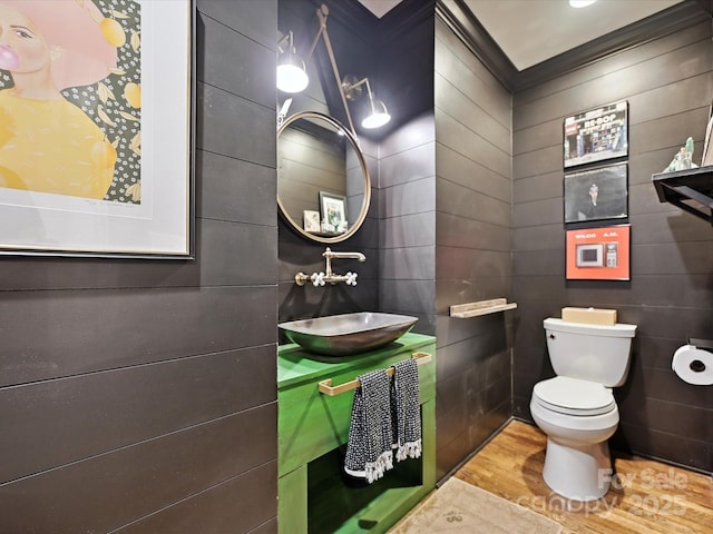 half bath with toilet, vanity, tile walls, and wood finished floors