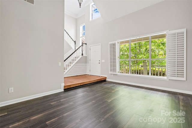 6434 Skyline Dr, Charlotte, NC 28269 - unfurnished living room featuring stairs, wood finished floors, a high ceiling, and baseboards