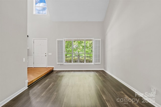 6434 Skyline Dr, Charlotte, NC 28269 - unfurnished living room featuring a high ceiling, dark wood-style flooring, plenty of natural light, and baseboards