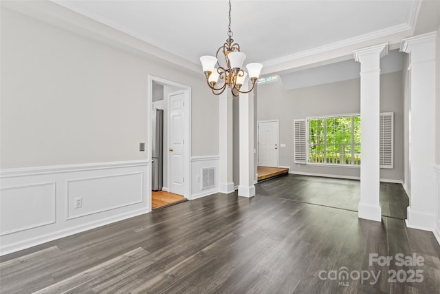 6434 Skyline Dr, Charlotte, NC 28269 - unfurnished dining area with wood finished floors, decorative columns, a chandelier, a wainscoted wall, and crown molding