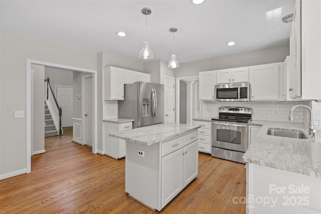 6434 Skyline Dr, Charlotte, NC 28269 - kitchen with stainless steel appliances, a sink, decorative backsplash, white cabinetry, and light wood-style flooring