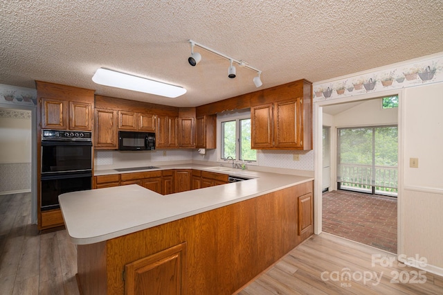 104 Ridge Dr, Stanley, NC 28164 - kitchen featuring black appliances, brown cabinets, a peninsula, light countertops, and a textured ceiling