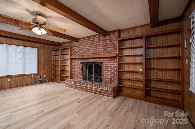104 Ridge Dr, Stanley, NC 28164 - unfurnished living room with wood walls, beamed ceiling, wood finished floors, a textured ceiling, and a fireplace