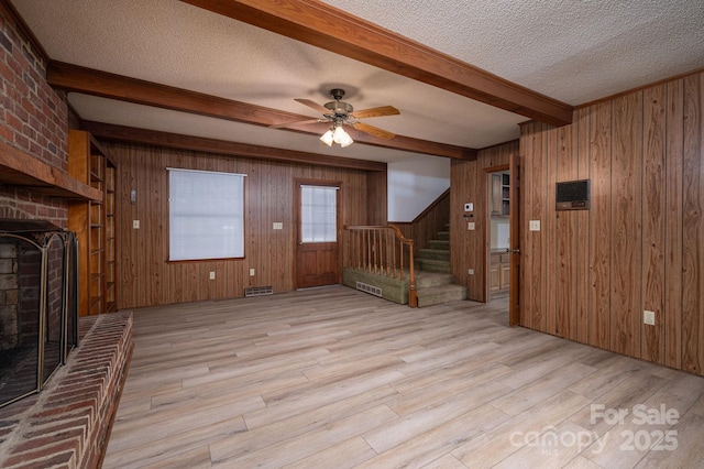 104 Ridge Dr, Stanley, NC 28164 - unfurnished living room with a brick fireplace, stairway, light wood finished floors, beamed ceiling, and wood walls