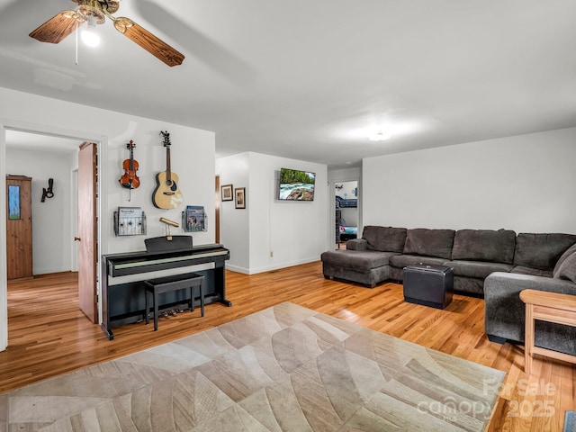living room featuring wood finished floors, ceiling fan, and baseboards