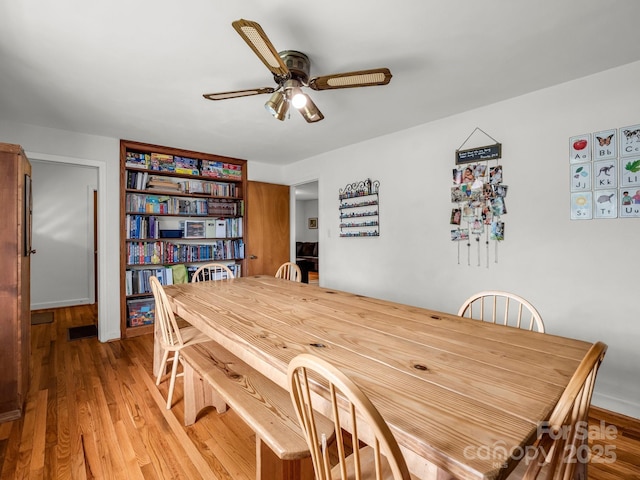 dining space featuring light wood-style floors, a ceiling fan, and baseboards