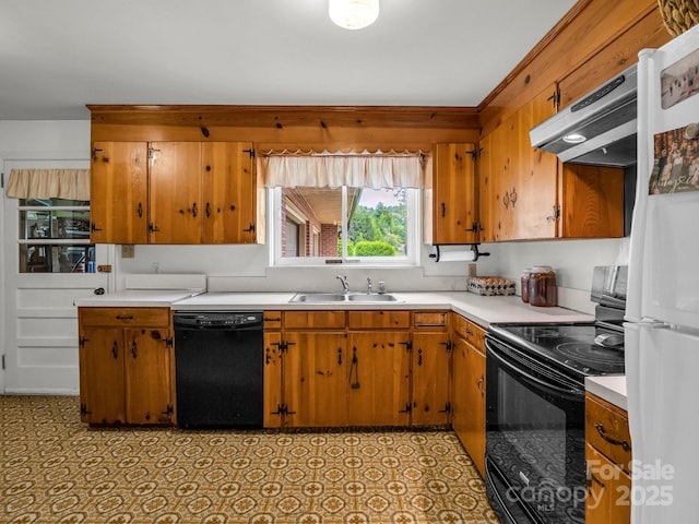 kitchen with black appliances, a sink, light countertops, and brown cabinets