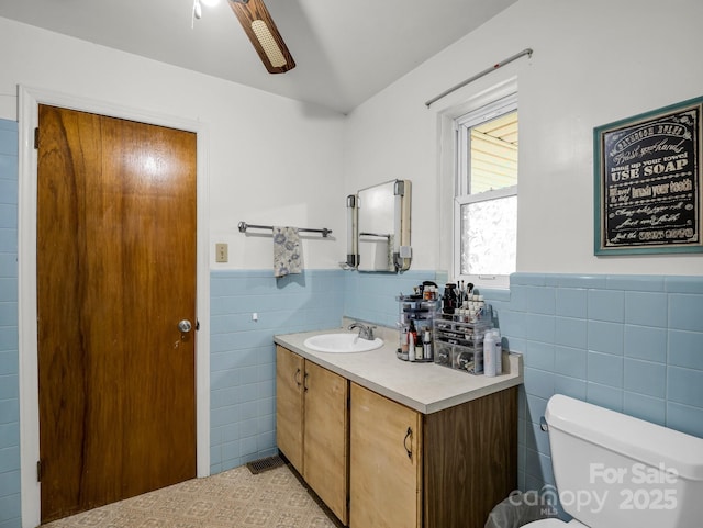 bathroom featuring tile walls, wainscoting, toilet, vanity, and tile patterned floors