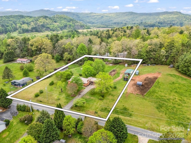 aerial view of property's location featuring property boundaries highlighted, a heavily wooded area, and a mountainous background