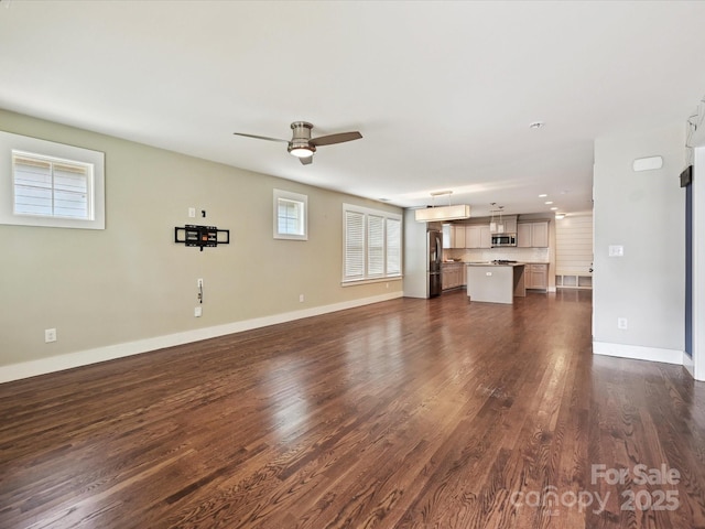 unfurnished living room featuring dark wood-style flooring, ceiling fan, and baseboards