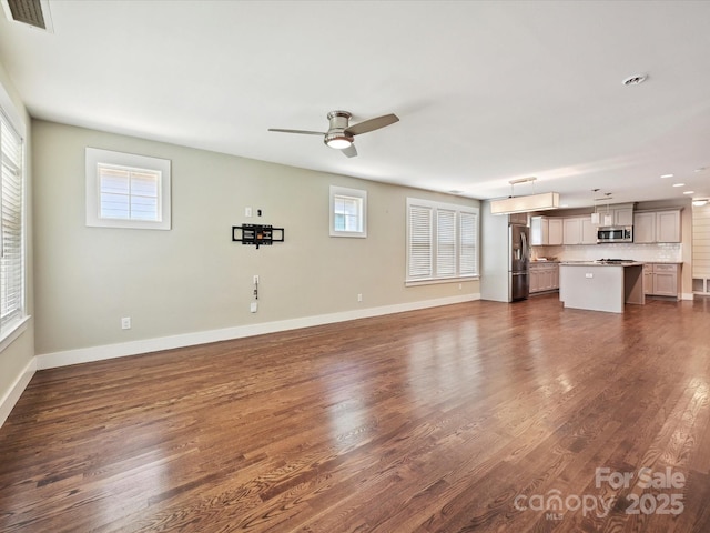 unfurnished living room with a ceiling fan, plenty of natural light, dark wood-style flooring, and baseboards