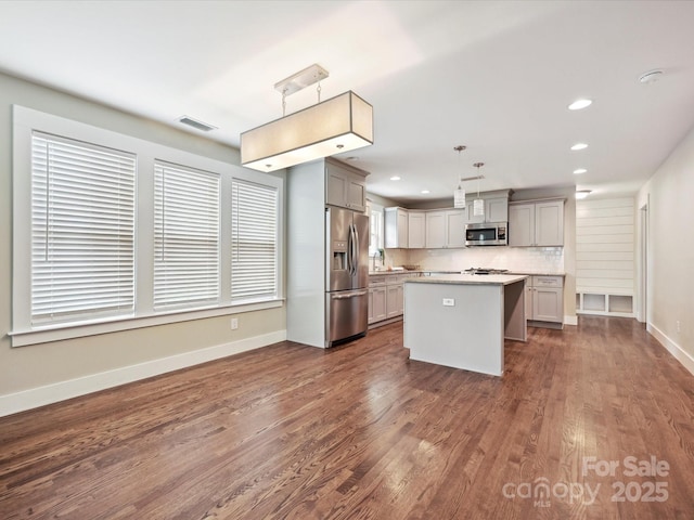 kitchen with appliances with stainless steel finishes, gray cabinetry, baseboards, light countertops, and recessed lighting